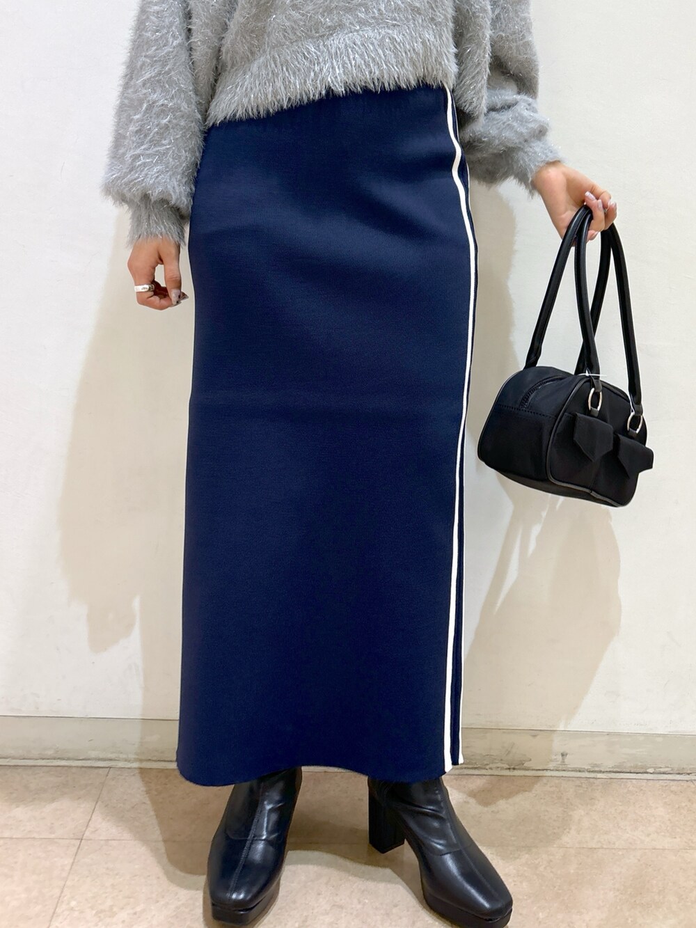 ブルー系のスカート、ブラック系のブーツ、ブラック系のトートバッグを着用したレディースの秋コーディネートの8枚目の写真