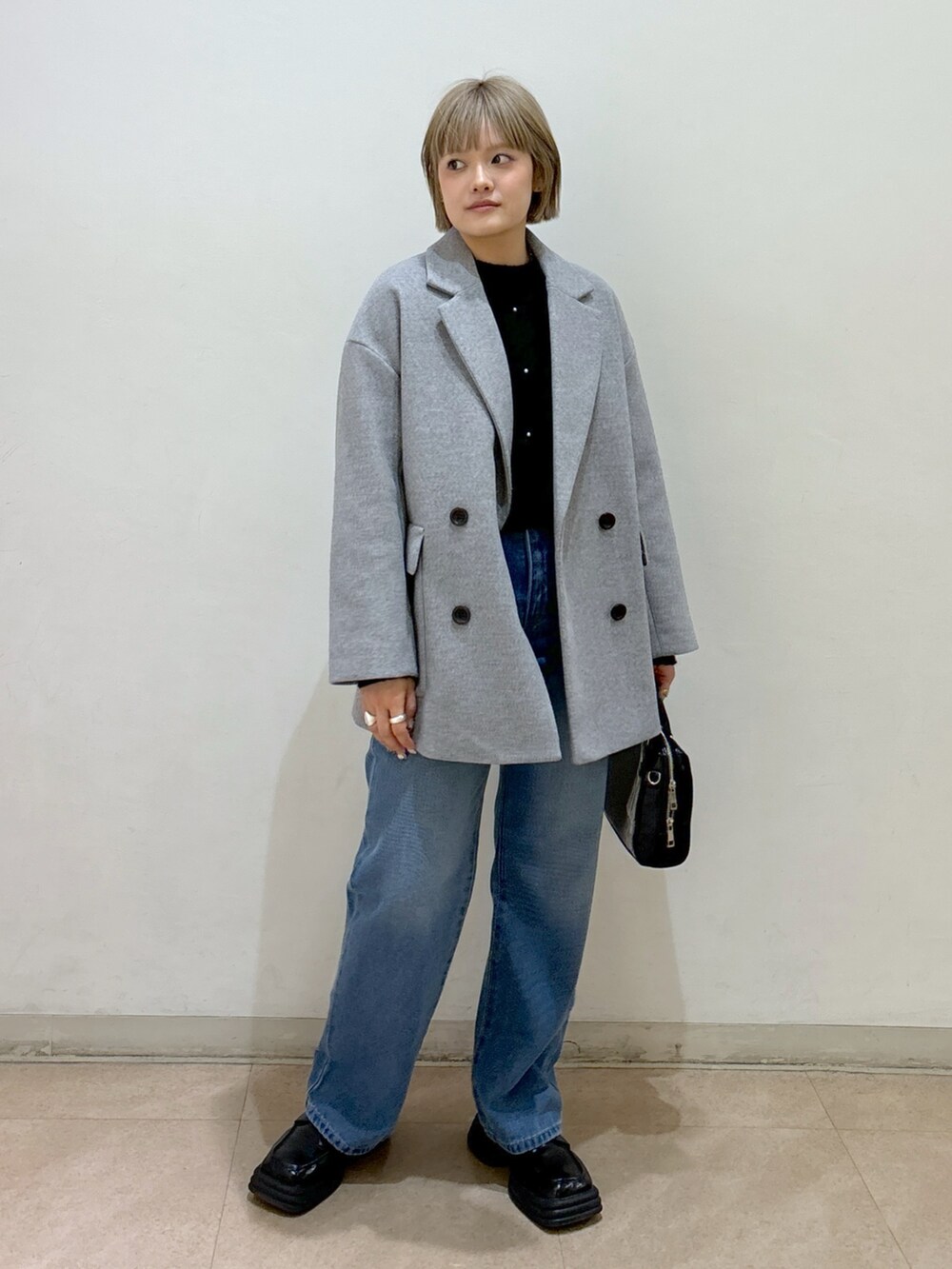 グレー系のピーコート、ブラック系のニット/セーター、ブルー系のデニムパンツを着用したレディースの冬コーディネートの4枚目の写真