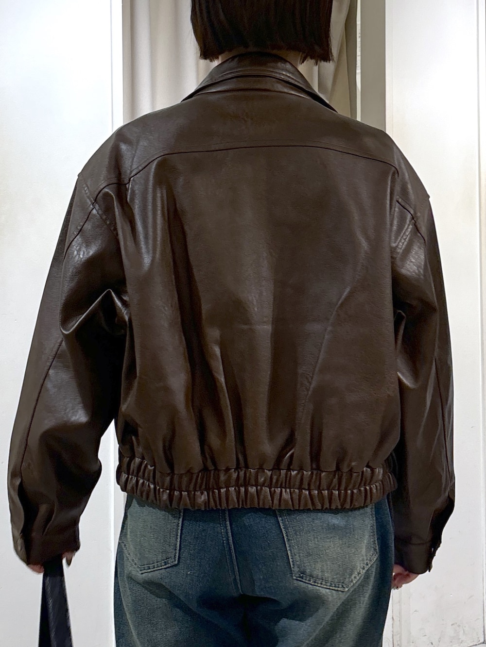 ブラウン系のブルゾン、グレー系のTシャツ/カットソー、ブルー系のデニムパンツを着用したレディースの秋コーディネートの6枚目の写真