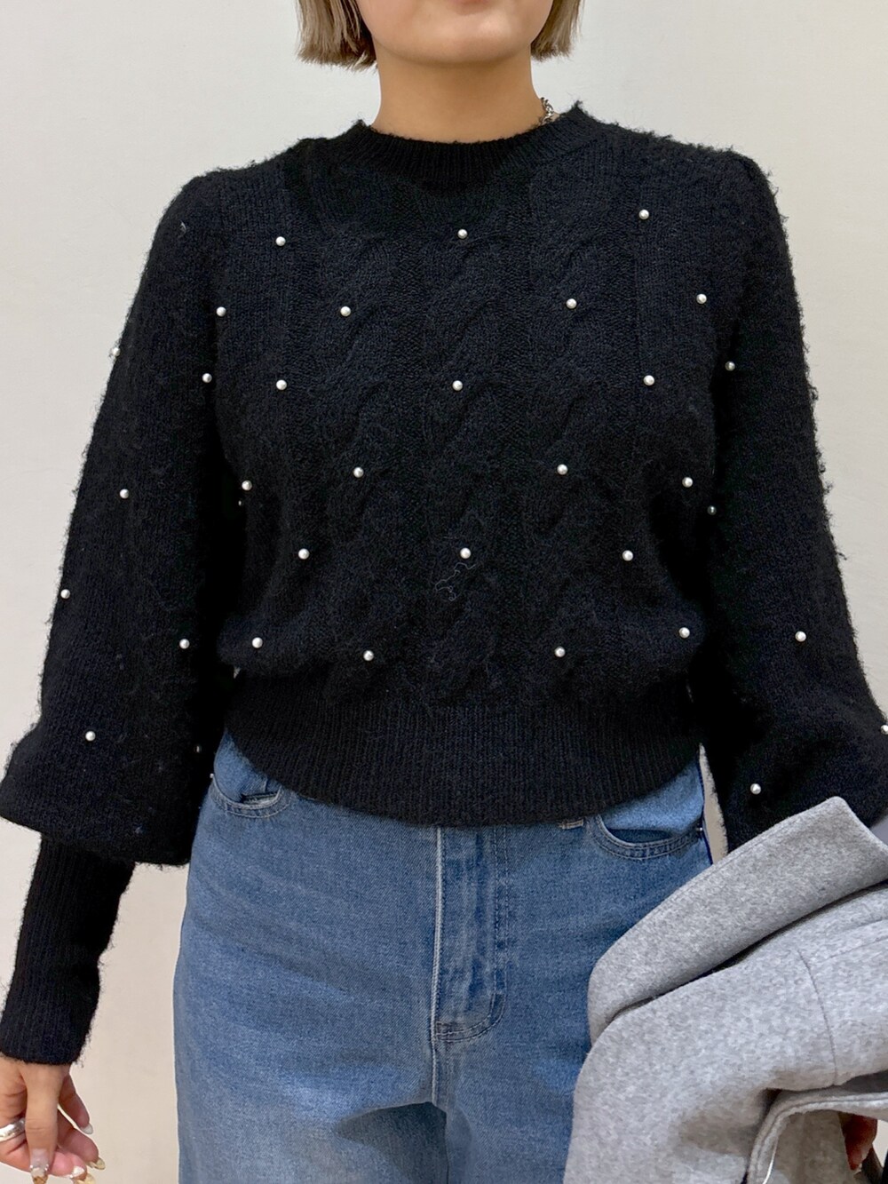 グレー系のピーコート、ブラック系のニット/セーター、ブルー系のデニムパンツを着用したレディースの冬コーディネートの8枚目の写真