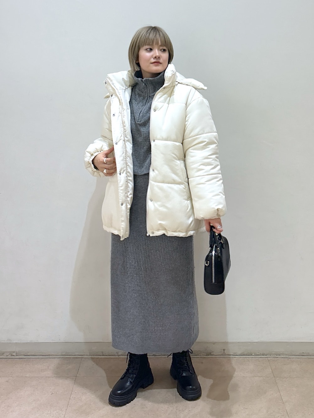 グレー系のワンピース、ホワイト系のダウンジャケット/コート、ブラック系のブーツを着用したレディースの冬コーディネートの2枚目の写真