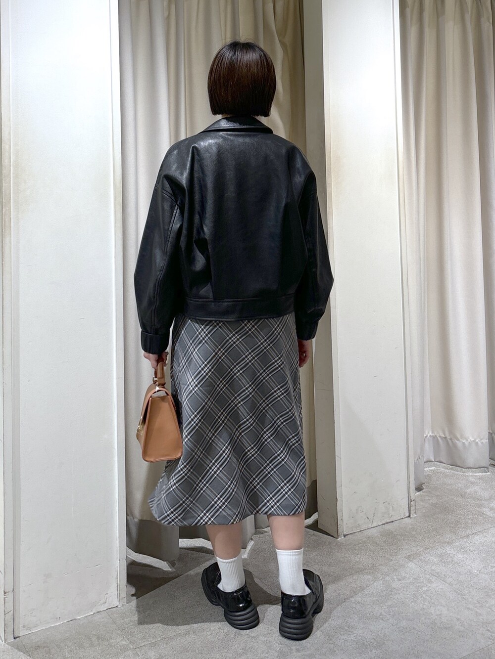 ブラック系のブルゾン、ブルー系のTシャツ/カットソー、ベージュ系のトートバッグを着用したレディースの秋コーディネートの4枚目の写真