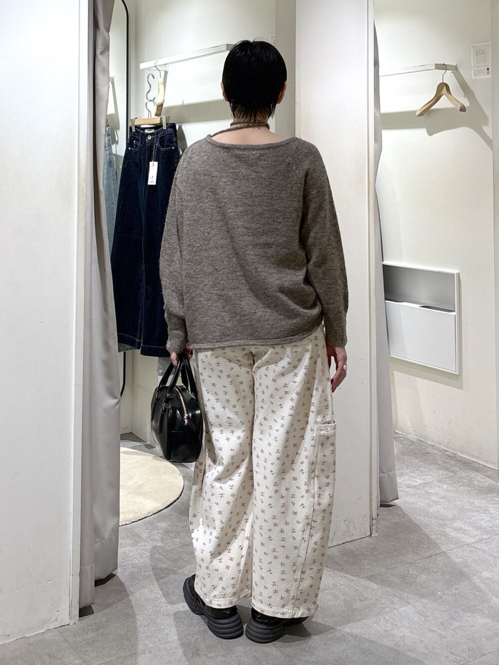 ブラウン系のニット/セーター、ホワイト系のデニムパンツ、ブラック系のハンドバッグを着用したレディースの冬コーディネートの3枚目の写真