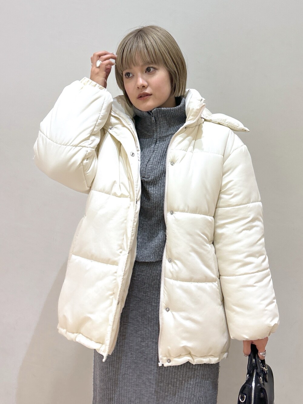 グレー系のワンピース、ホワイト系のダウンジャケット/コート、ブラック系のブーツを着用したレディースの冬コーディネートの4枚目の写真