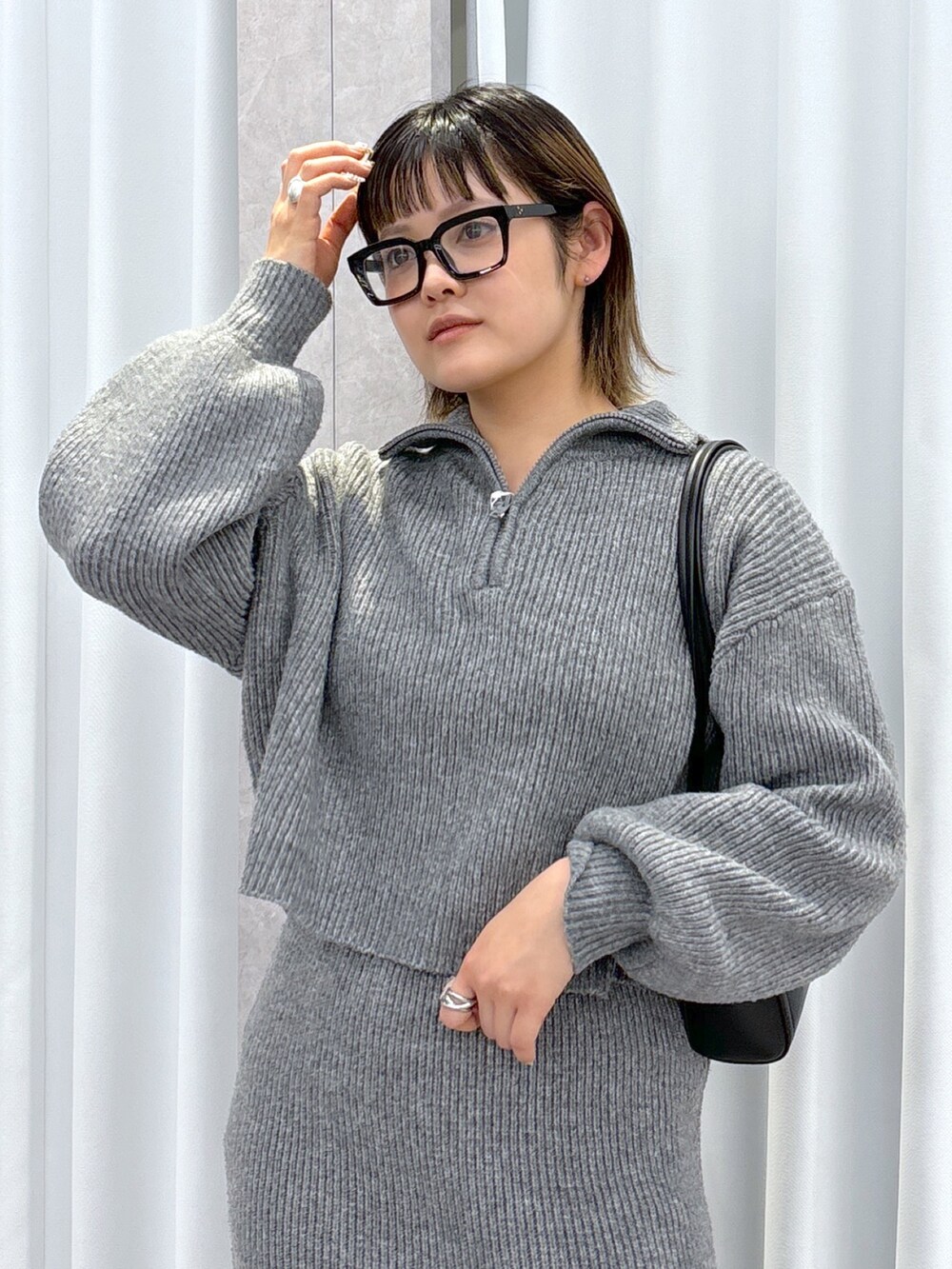 グレー系のワンピース、ブラック系のブーツ、ブラック系のショルダーバッグを着用したレディースの冬コーディネートの4枚目の写真