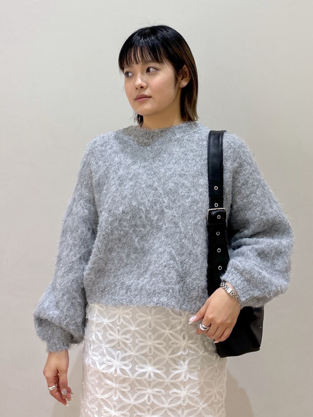 グレー系のニット/セーター、ホワイト系のスカート、ブルー系のショルダーバッグを着用したレディースの冬コーディネートの4枚目の写真