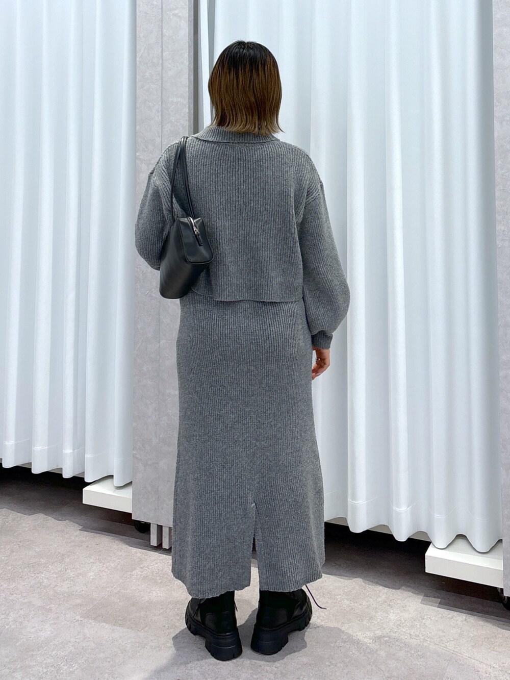 グレー系のワンピース、ブラック系のブーツ、ブラック系のショルダーバッグを着用したレディースの冬コーディネートの3枚目の写真