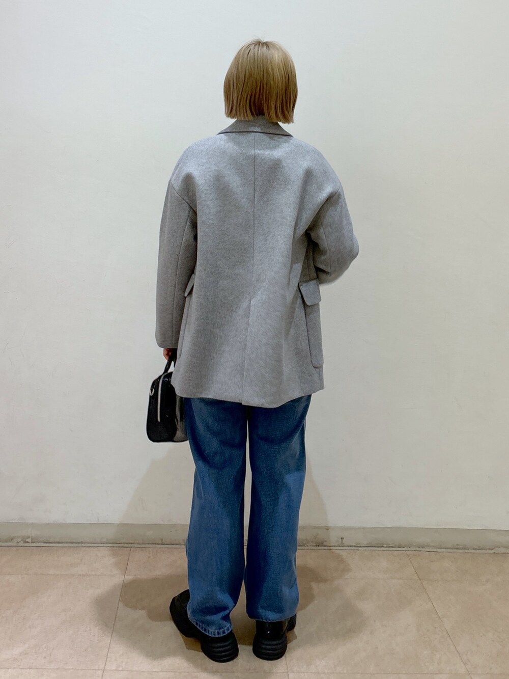 グレー系のピーコート、ブラック系のニット/セーター、ブルー系のデニムパンツを着用したレディースの冬コーディネートの3枚目の写真