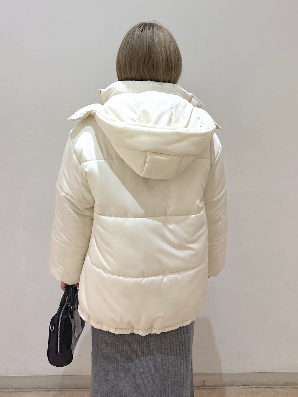 グレー系のワンピース、ホワイト系のダウンジャケット/コート、ブラック系のブーツを着用したレディースの冬コーディネートの5枚目の写真