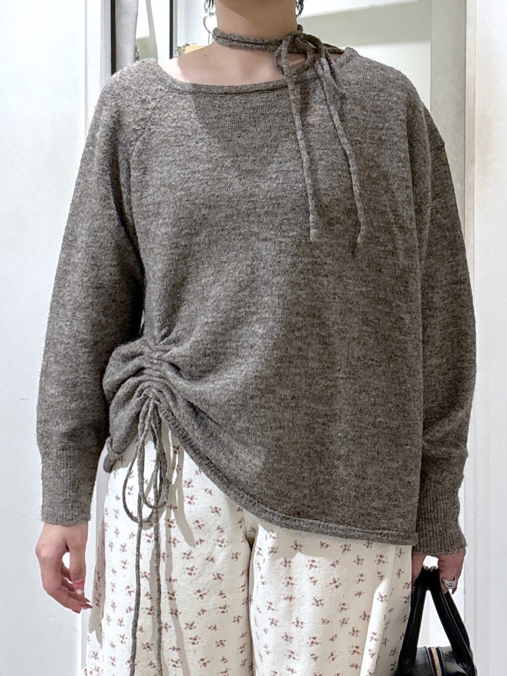 ブラウン系のニット/セーター、ホワイト系のデニムパンツ、ブラック系のハンドバッグを着用したレディースの冬コーディネートの4枚目の写真