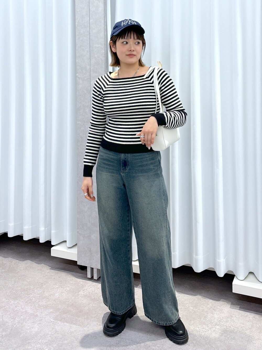 ホワイト系のニット/セーター、ブルー系のデニムパンツ、ホワイト系のショルダーバッグを着用したレディースの冬コーディネートの6枚目の写真