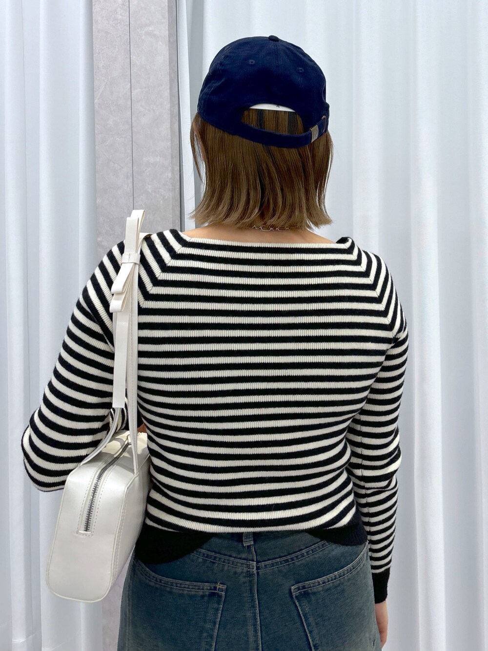 ホワイト系のニット/セーター、ブルー系のデニムパンツ、ホワイト系のショルダーバッグを着用したレディースの冬コーディネートの5枚目の写真