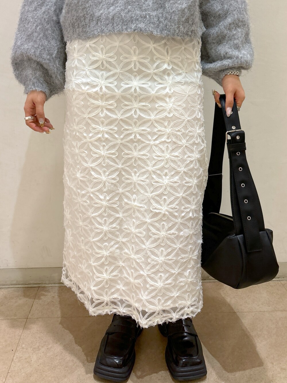 グレー系のニット/セーター、ホワイト系のスカート、ブルー系のショルダーバッグを着用したレディースの冬コーディネートの6枚目の写真