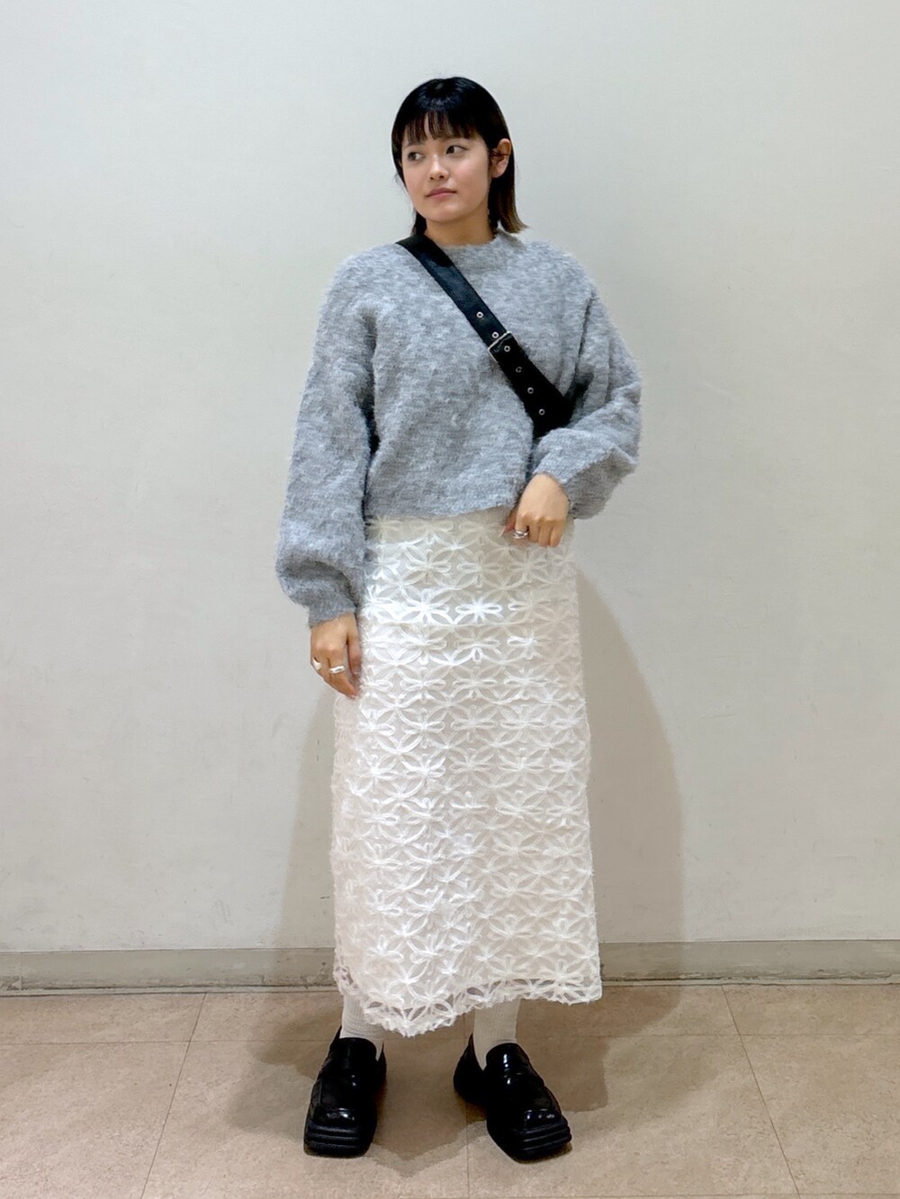 グレー系のニット/セーター、ホワイト系のスカート、ブルー系のショルダーバッグを着用したレディースの冬コーディネートの2枚目の写真
