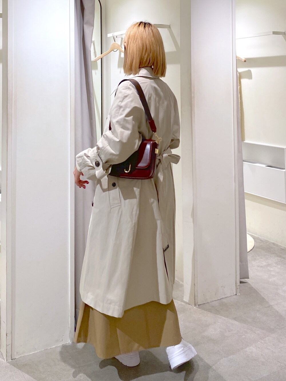 ベージュ系のトレンチコート、ベージュ系のスカート、ブラウン系のショルダーバッグを着用したレディースの冬コーディネートの6枚目の写真