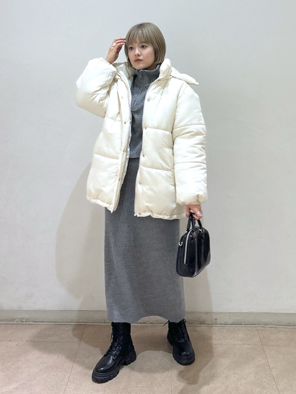 グレー系のワンピース、ホワイト系のダウンジャケット/コート、ブラック系のブーツを着用したレディースの冬コーディネートの6枚目の写真