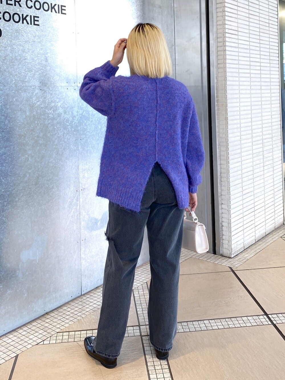 ブルー系のニット/セーター、ホワイト系のショルダーバッグ、ブラック系のデニムパンツを着用したレディースの秋コーディネートの4枚目の写真