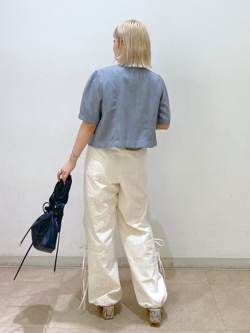 グレー系のノーカラージャケット、ホワイト系のカーゴパンツ、ブラック系のショルダーバッグを着用したレディースの春コーディネートの4枚目の写真
