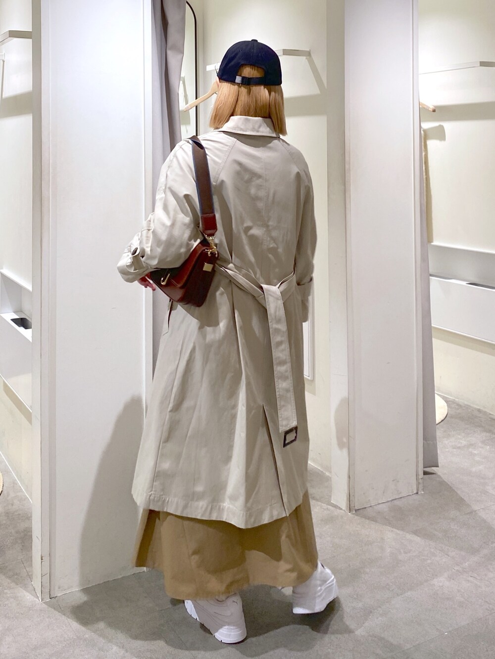 ベージュ系のトレンチコート、ベージュ系のスカート、ブラウン系のショルダーバッグを着用したレディースの冬コーディネートの3枚目の写真