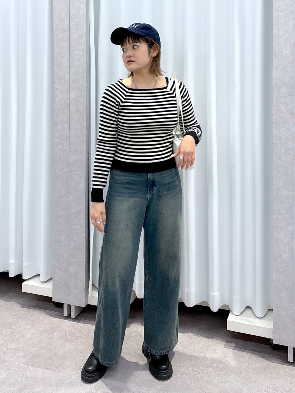 ホワイト系のニット/セーター、ブルー系のデニムパンツ、ホワイト系のショルダーバッグを着用したレディースの冬コーディネートの2枚目の写真