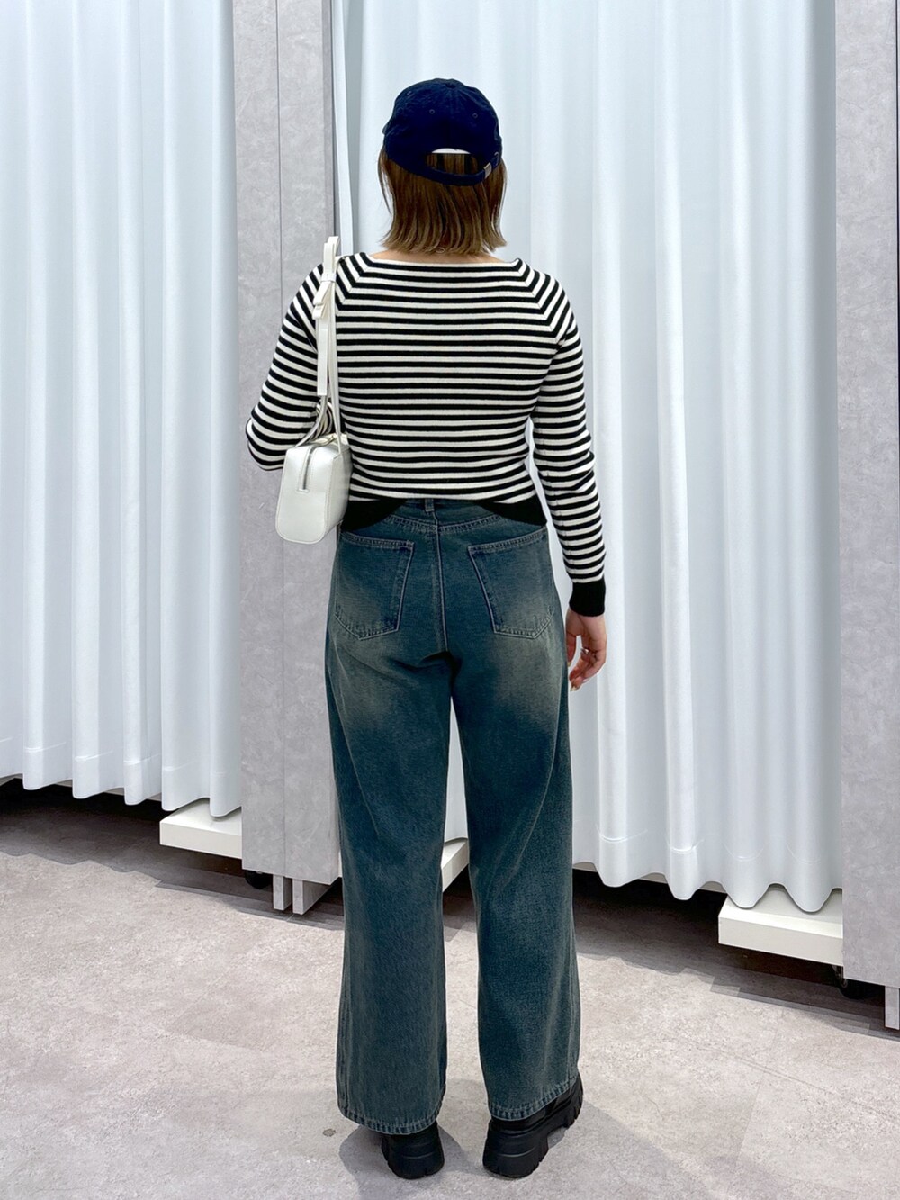 ホワイト系のニット/セーター、ブルー系のデニムパンツ、ホワイト系のショルダーバッグを着用したレディースの冬コーディネートの3枚目の写真