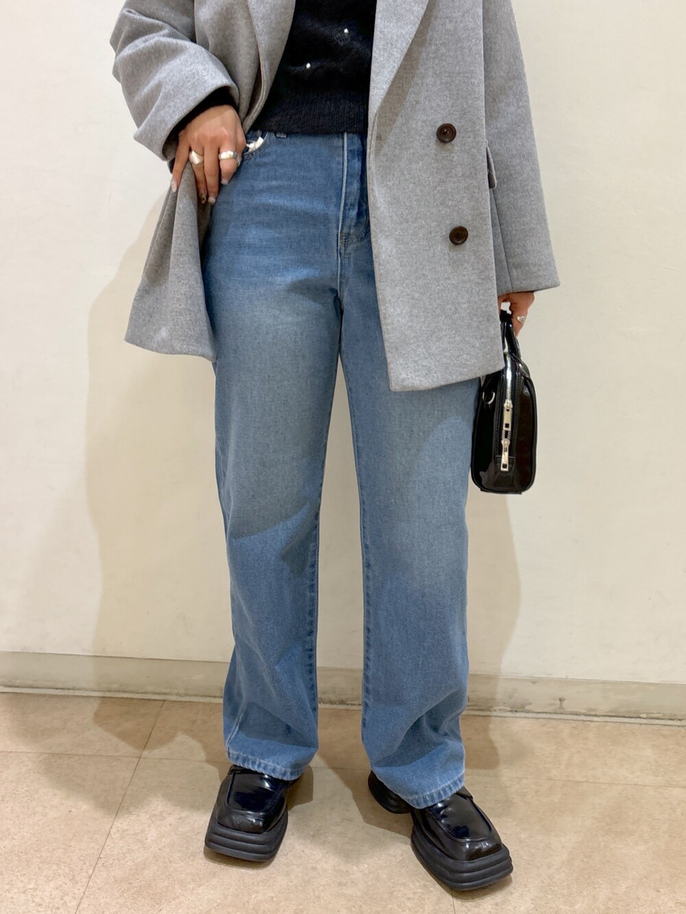 グレー系のピーコート、ブラック系のニット/セーター、ブルー系のデニムパンツを着用したレディースの冬コーディネートの9枚目の写真