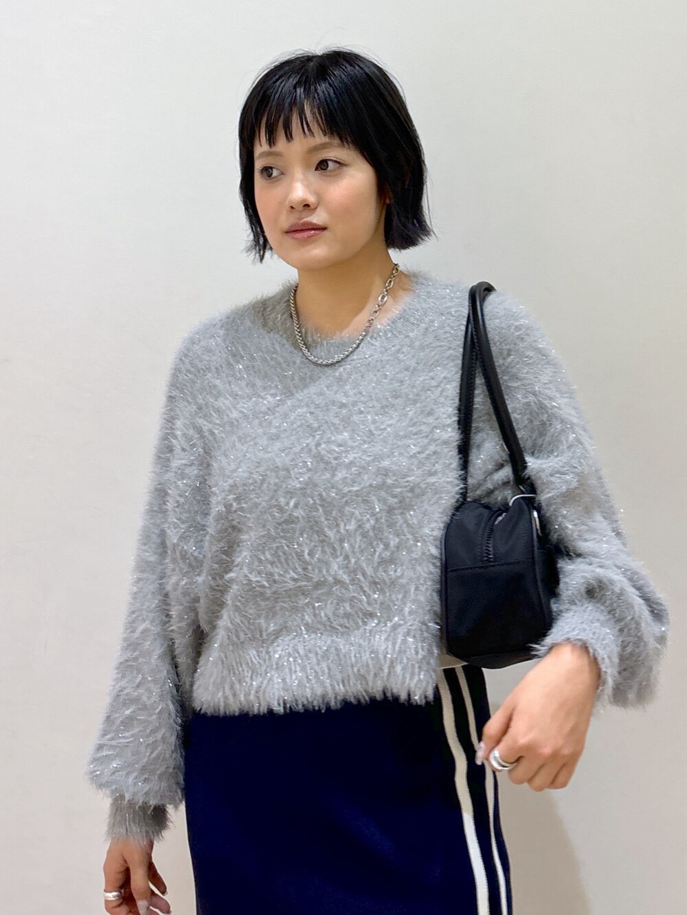 ブルー系のスカート、ブラック系のブーツ、ブラック系のトートバッグを着用したレディースの秋コーディネートの4枚目の写真