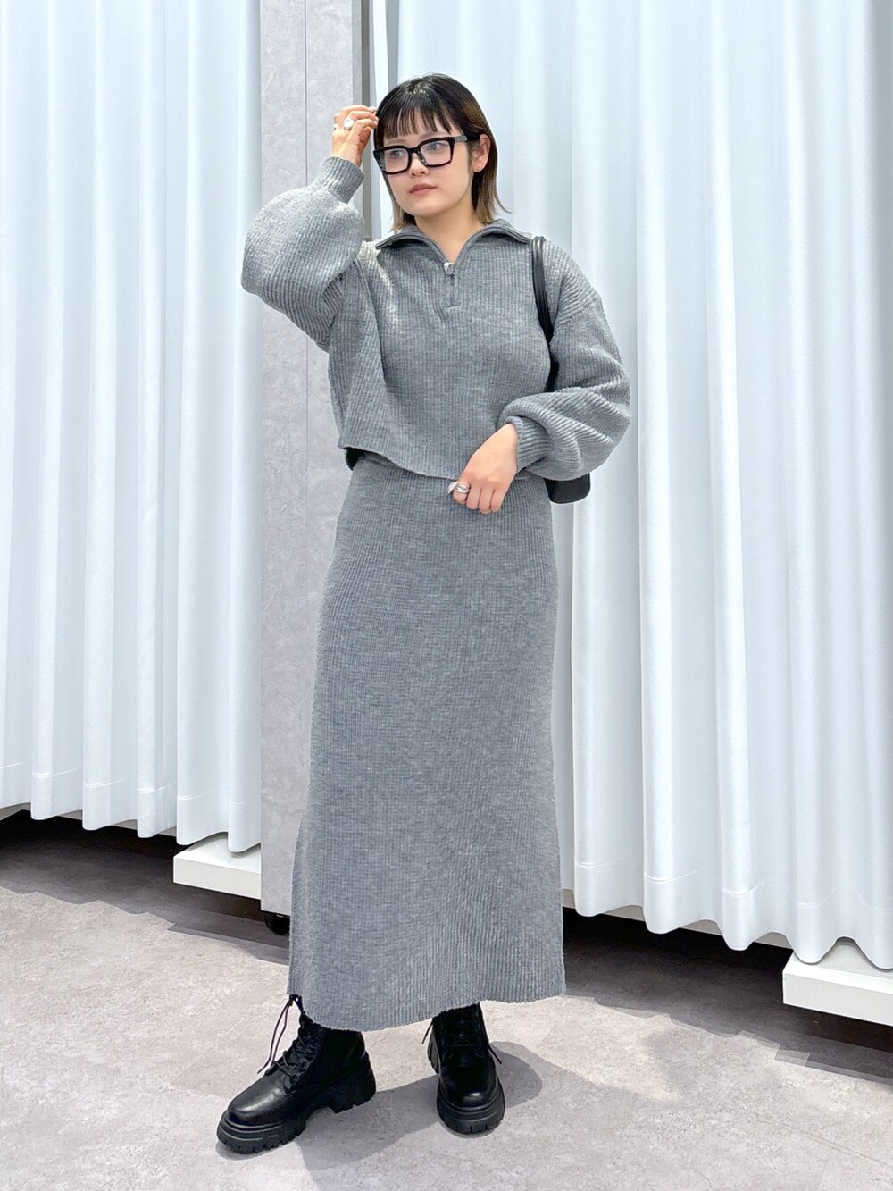 グレー系のワンピース、ブラック系のブーツ、ブラック系のショルダーバッグを着用したレディースの冬コーディネートの2枚目の写真