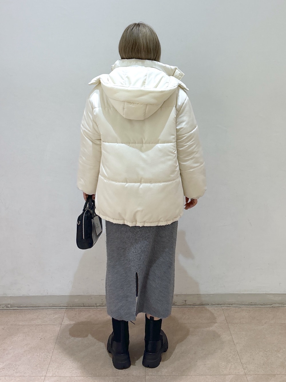 グレー系のワンピース、ホワイト系のダウンジャケット/コート、ブラック系のブーツを着用したレディースの冬コーディネートの3枚目の写真