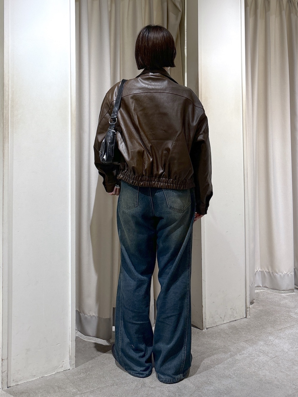 ブラウン系のブルゾン、グレー系のTシャツ/カットソー、ブルー系のデニムパンツを着用したレディースの秋コーディネートの4枚目の写真