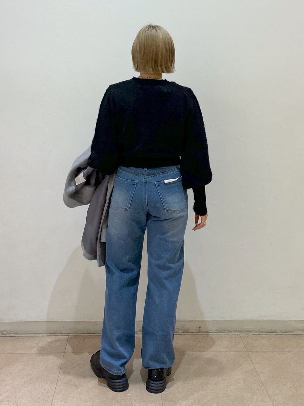 グレー系のピーコート、ブラック系のニット/セーター、ブルー系のデニムパンツを着用したレディースの冬コーディネートの7枚目の写真