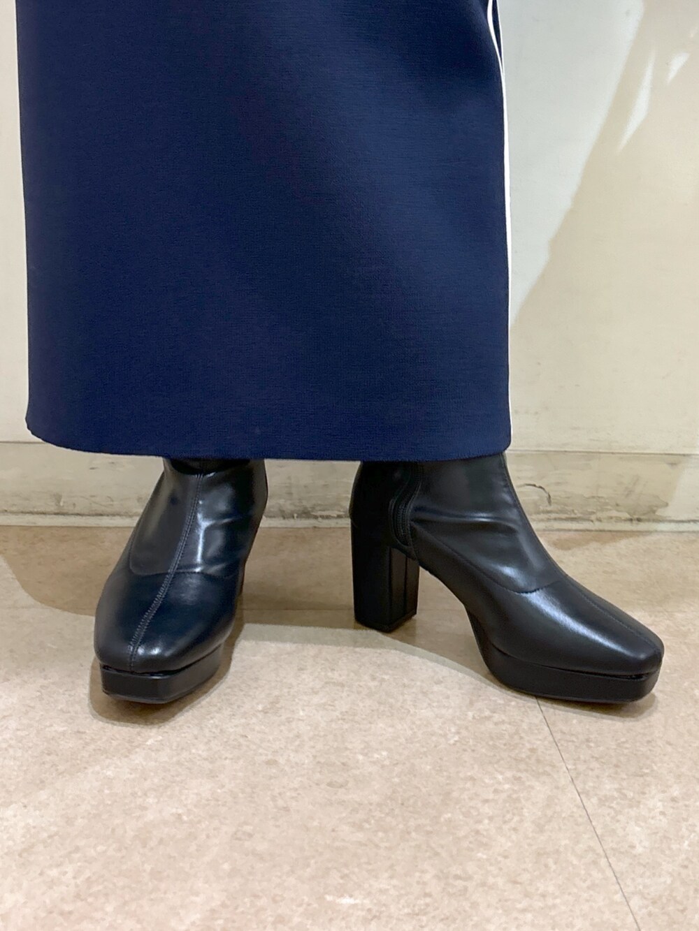 ブルー系のスカート、ブラック系のブーツ、ブラック系のトートバッグを着用したレディースの秋コーディネートの9枚目の写真