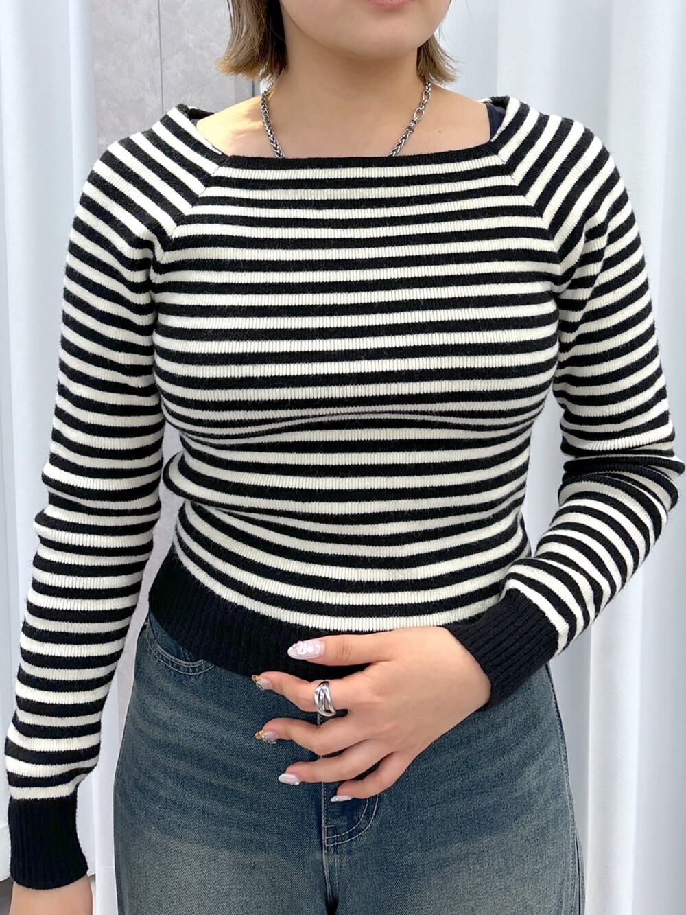 ホワイト系のニット/セーター、ブルー系のデニムパンツ、ホワイト系のショルダーバッグを着用したレディースの冬コーディネートの7枚目の写真