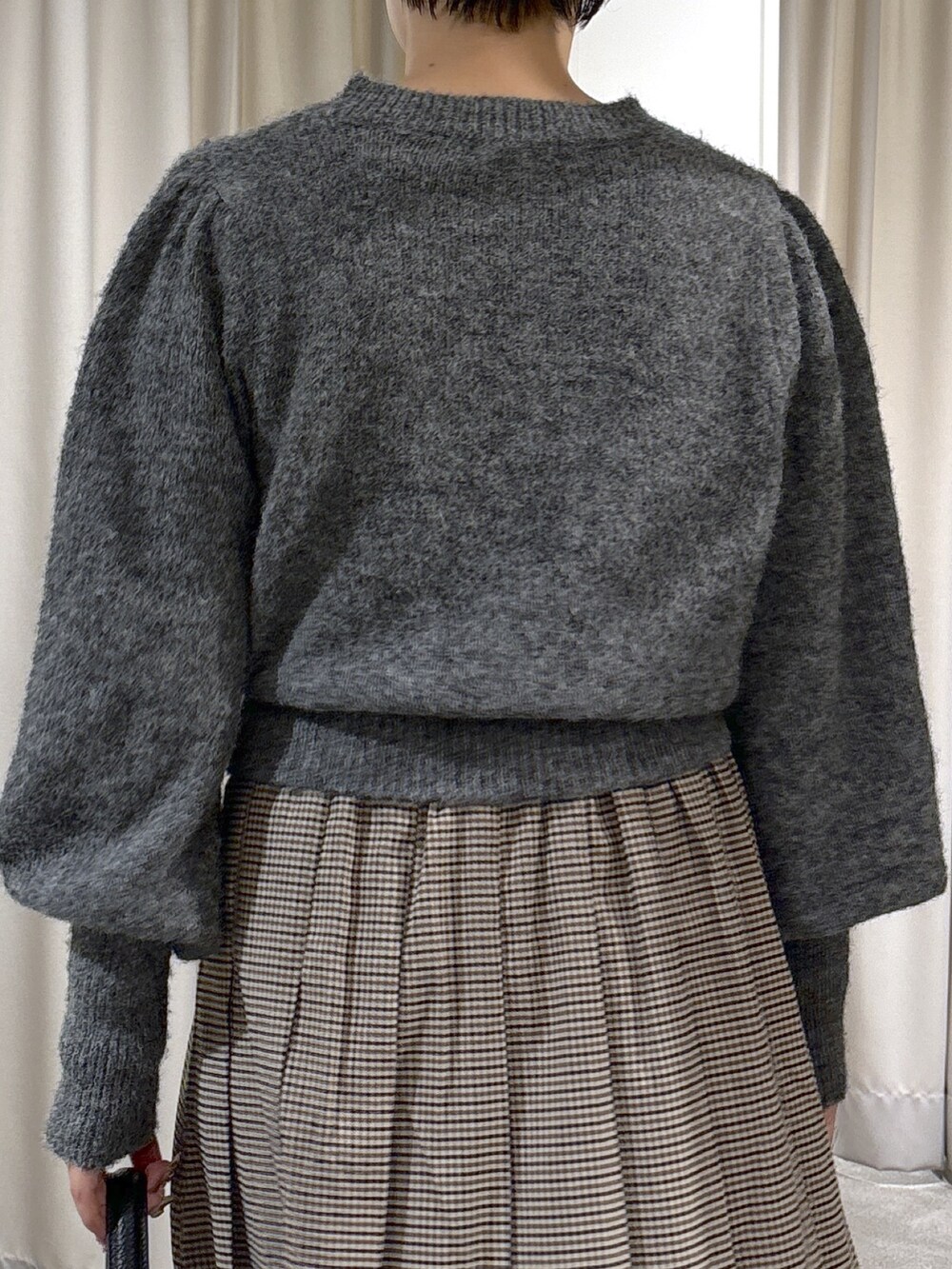 グレー系のニット/セーター、ベージュ系のスカート、ブラック系のショルダーバッグを着用したレディースの秋コーディネートの5枚目の写真