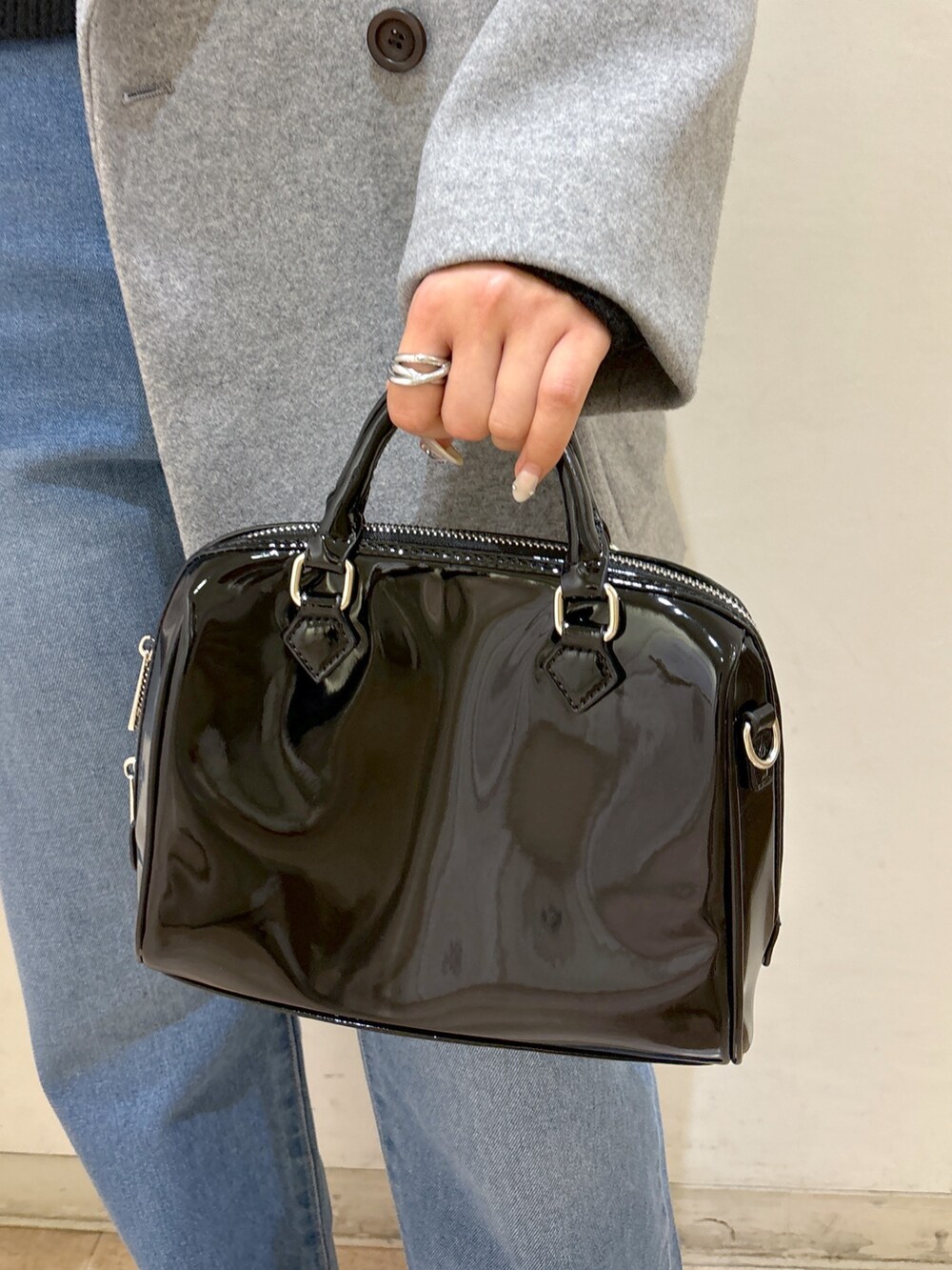 グレー系のピーコート、ブラック系のニット/セーター、ブルー系のデニムパンツを着用したレディースの冬コーディネートの10枚目の写真