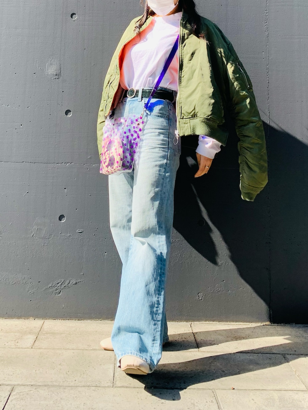 パープル系のショルダーバッグ、ブルー系のデニムパンツ、グリーン系のMA-1を着用したレディースの秋コーディネートの2枚目の写真