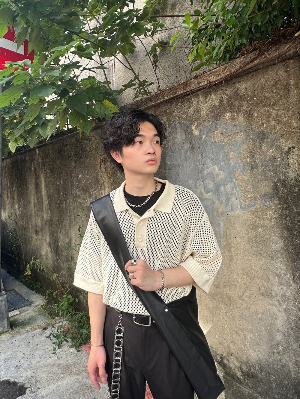 ベージュ系のポロシャツ、ブラック系のショルダーバッグ、ブラック系のスラックスを着用したメンズの夏コーディネートの2枚目の写真