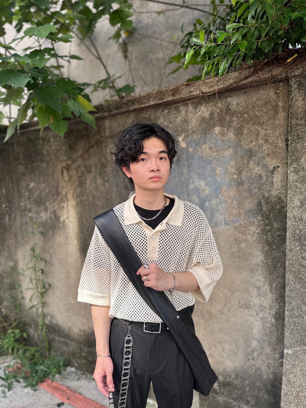 ベージュ系のポロシャツ、ブラック系のショルダーバッグ、ブラック系のスラックスを着用したメンズの夏コーディネートの3枚目の写真