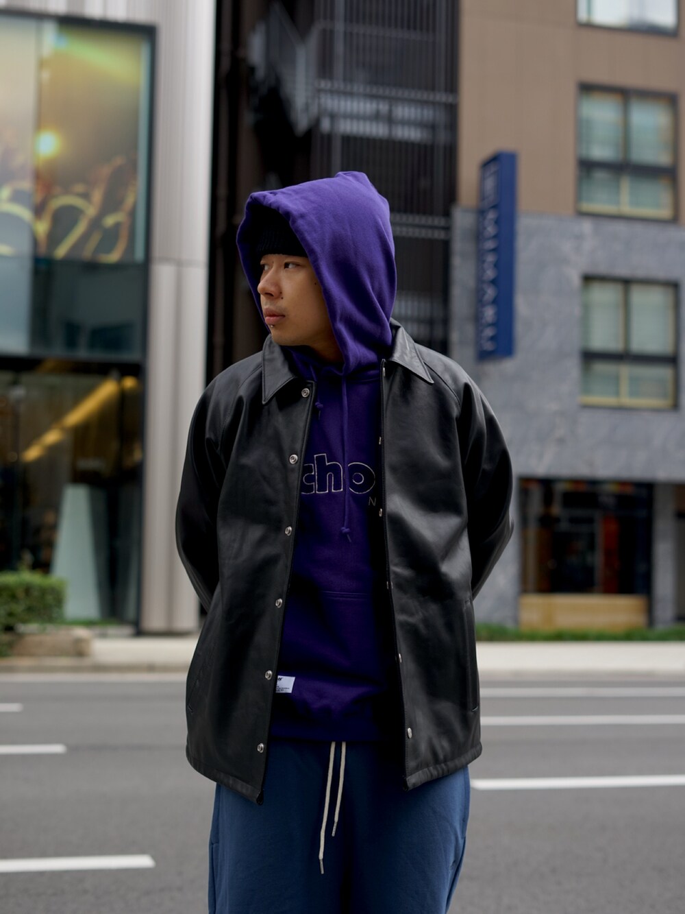 パープル系のパーカー、ブラック系のライダースジャケット、ブルー系のスウェットパンツを着用したメンズの秋コーディネートの3枚目の写真