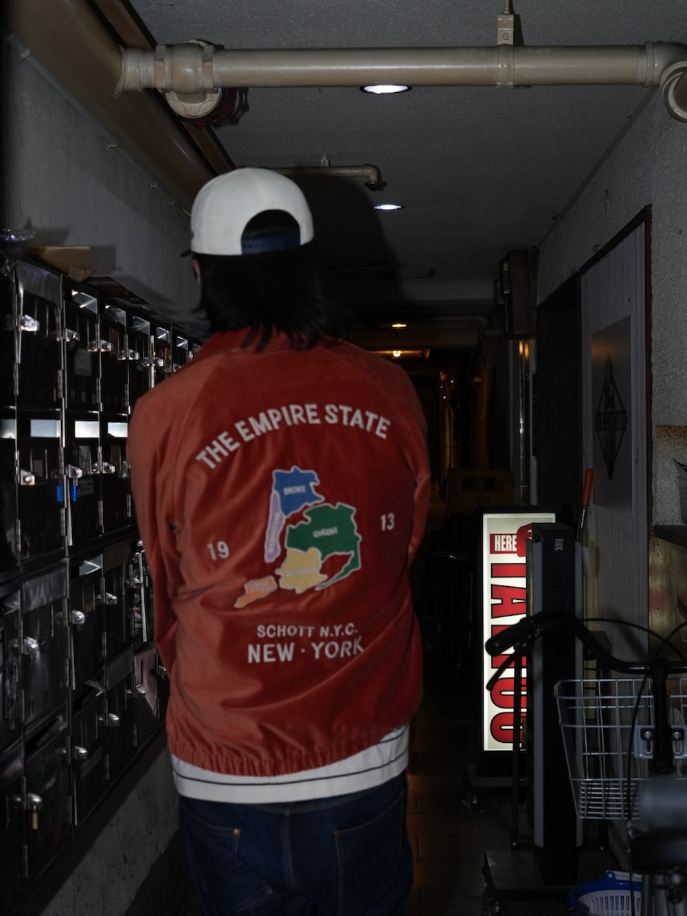 オレンジ系のブルゾン、その他のデニムパンツ、ベージュ系のTシャツ/カットソーを着用したメンズの秋コーディネートの3枚目の写真