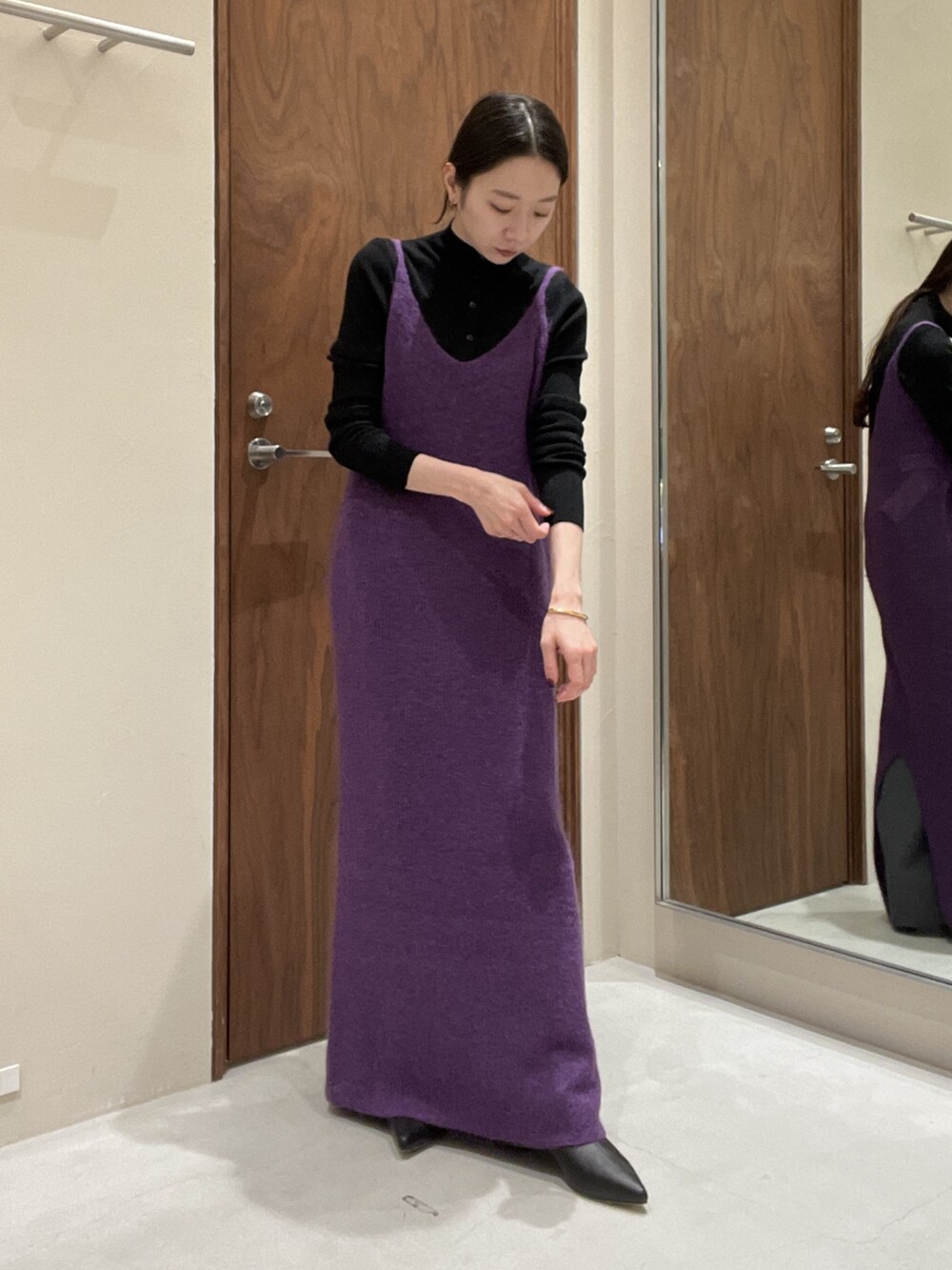 パープル系のワンピース、ブラック系のニット/セーターを着用したレディースの秋コーディネートの3枚目の写真