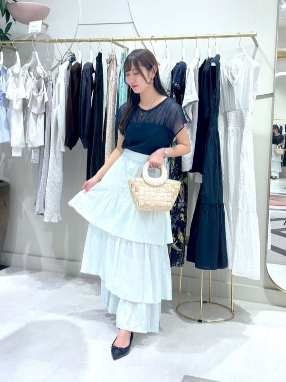 ブルー系のスカート、ブルー系のTシャツ/カットソー、ベージュ系のトートバッグを着用したレディースの夏コーディネートの2枚目の写真