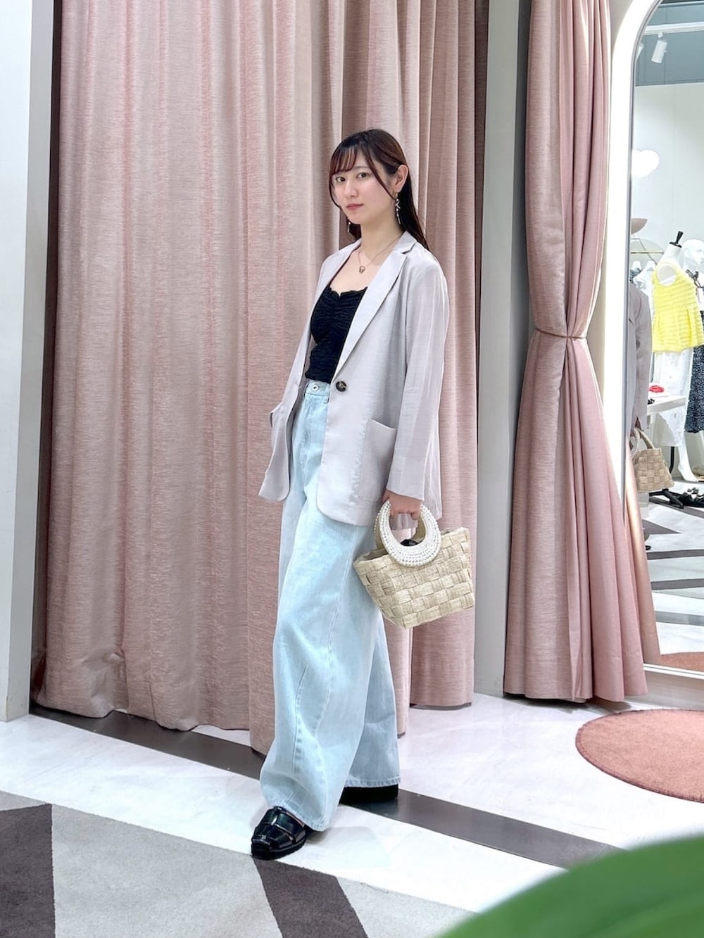 ベージュ系のテーラードジャケット、ブルー系のデニムパンツ、ブラック系のキャミソールを着用したレディースの夏コーディネートの2枚目の写真