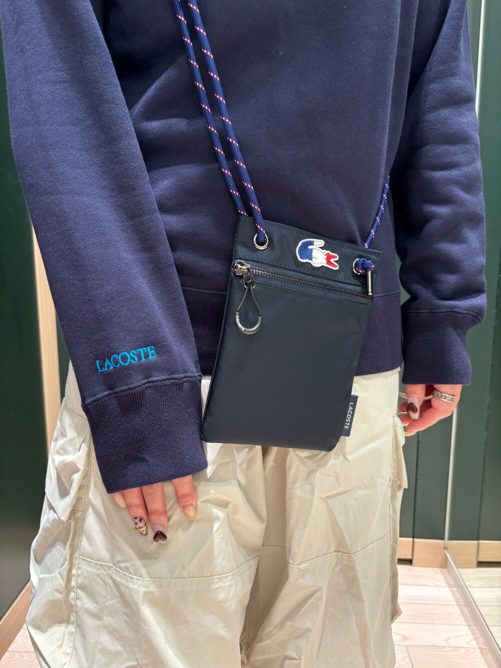 ホワイト系のスニーカー、ホワイト系のカーゴパンツ、ブルー系のクラッチバッグを着用したレディースの夏コーディネートの4枚目の写真