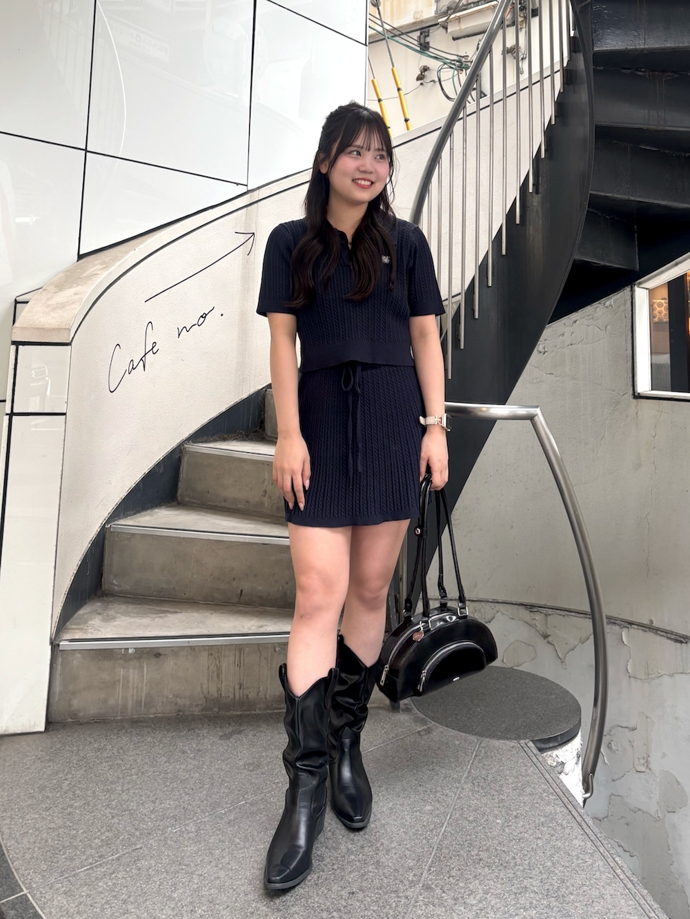 ブルー系のニット/セーター、ブルー系のスカート、ブラック系のボストンバッグを着用したレディースの春コーディネートの2枚目の写真