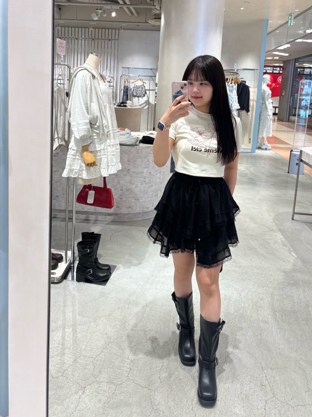 ブラック系のブーツ、ブラック系のボストンバッグ、ブラック系のスカートを着用したレディースの春コーディネートの4枚目の写真