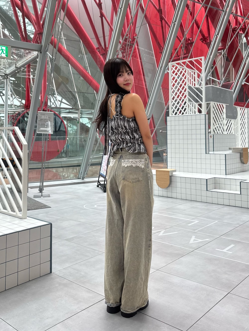 ブラック系のワンピース、ブルー系のデニムパンツ、ブラック系のサンダルを着用したレディースの春コーディネートの2枚目の写真