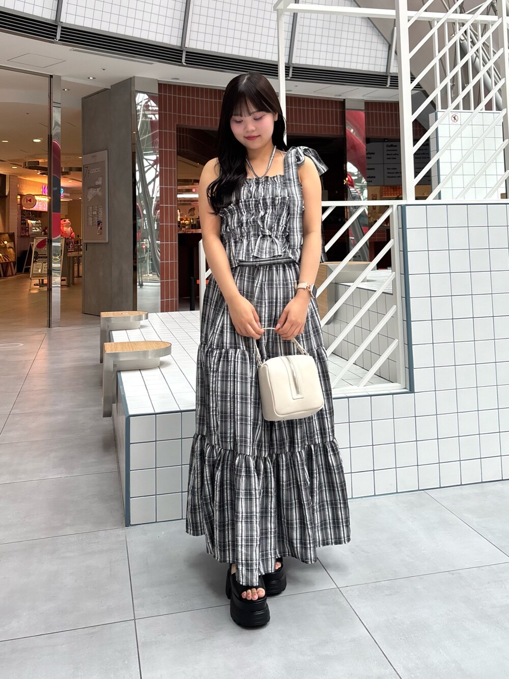 ブラック系のワンピース、ブルー系のデニムパンツ、ブラック系のサンダルを着用したレディースの春コーディネートの5枚目の写真