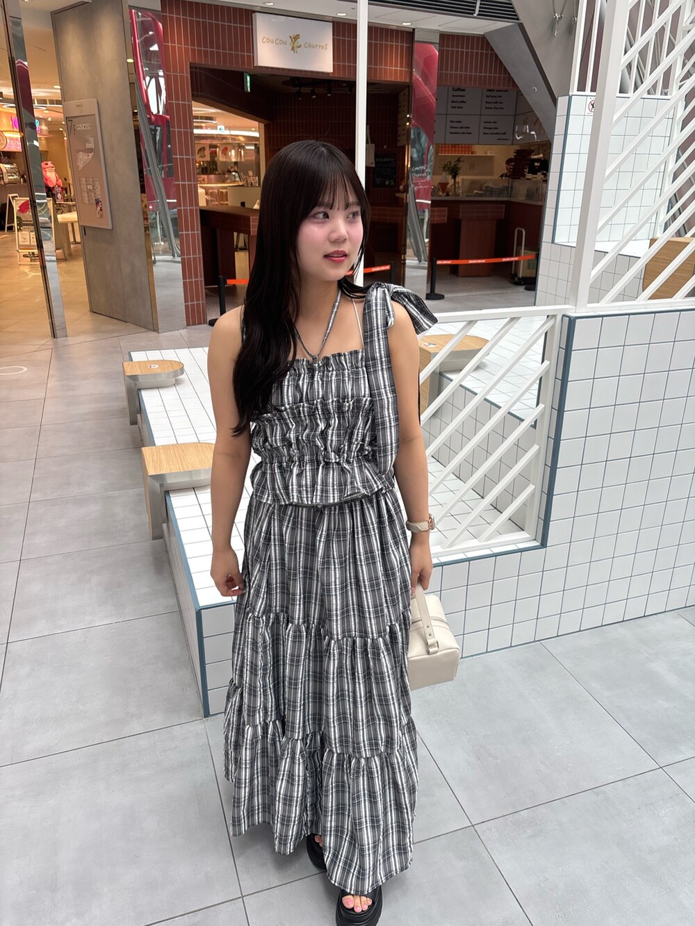 ブラック系のワンピース、ブラック系のサンダル、ホワイト系のショルダーバッグを着用したレディースの春コーディネートの4枚目の写真