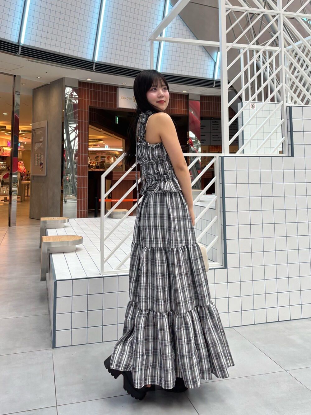 ブラック系のワンピース、ブラック系のサンダル、ホワイト系のショルダーバッグを着用したレディースの春コーディネートの2枚目の写真